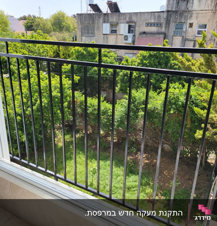 מעקה מתכת שחור במרפסת עם מסגרת חלון לבנה
